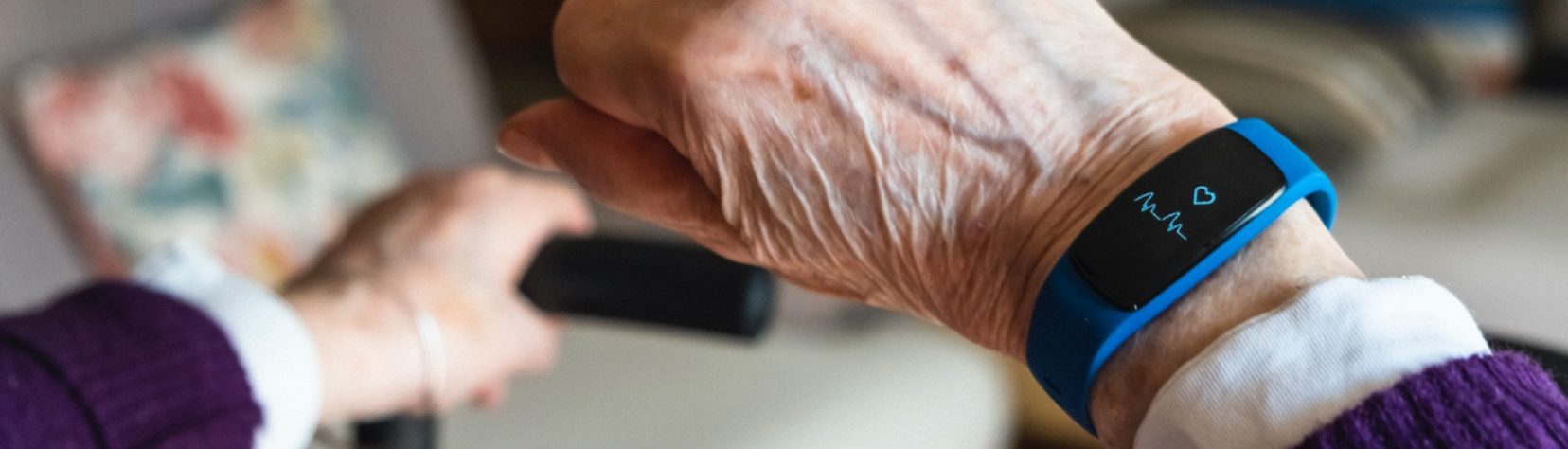 wearable device on older woman's wrist showing her heart rate