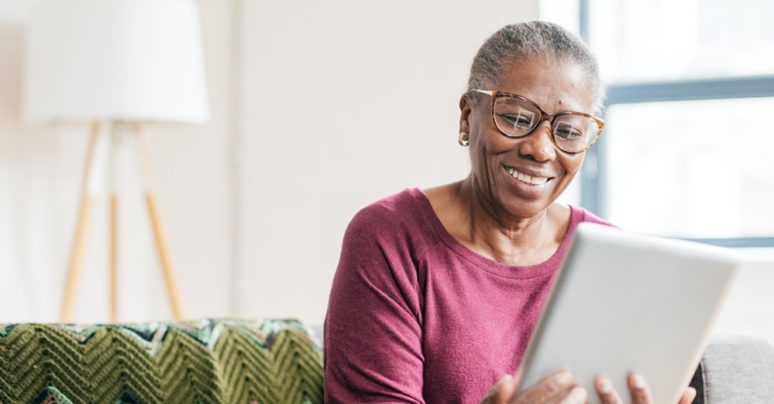 black older woman with glasses looking on ipad screen
